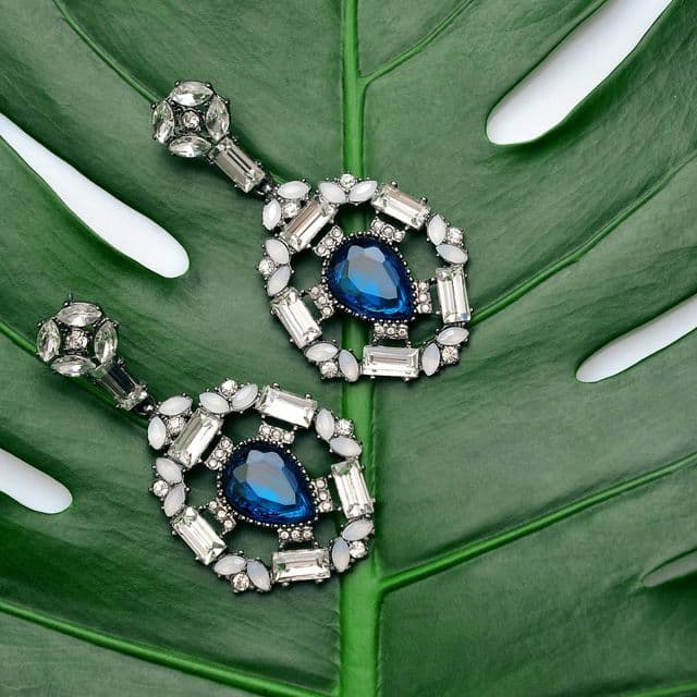 Boucles d’oreilles en cristal posées sur une feuille verte
