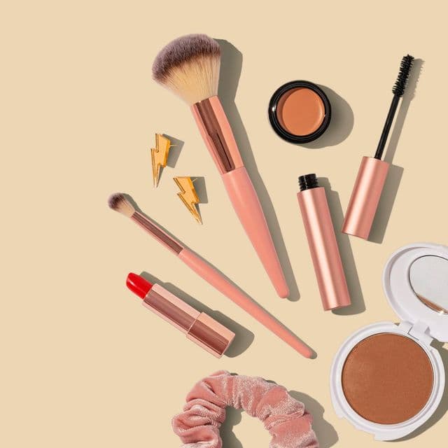 Pinceaux, poudres et rouge à lèvres sur fond beige